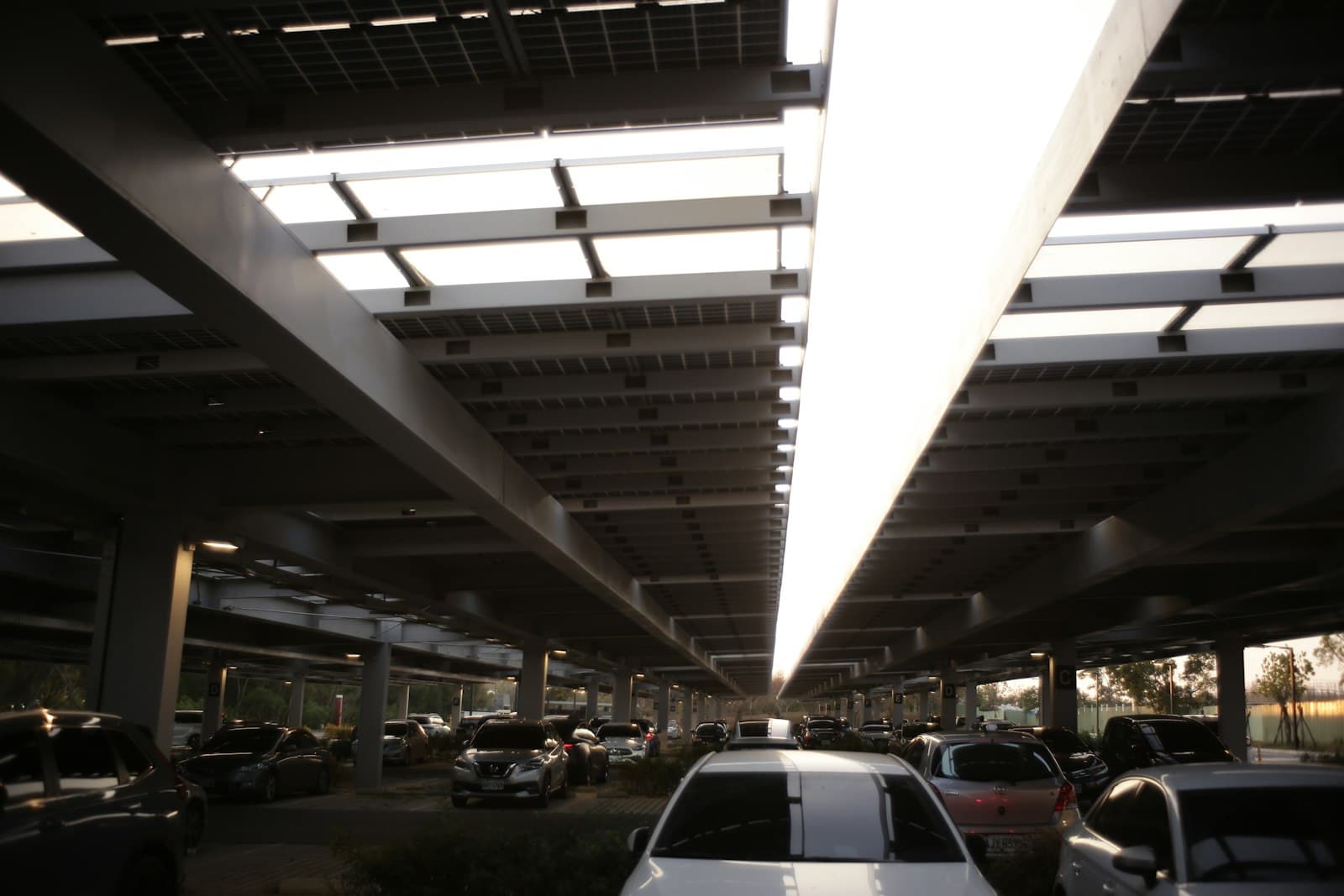 Voitures stationnées sous une ombrière photovoltaïque en plein soleil dans une zone résidentielle